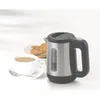 A stainless steel electric kettle with a black handle and base, placed next to a cup of coffee and a plate of cookies. Podgląd zdjęcia produktu