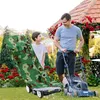 A father and son are in a garden, with the father operating a lawnmower and the son standing next to a camouflage-covered lawnmower cover. Produktbild-Vorschau