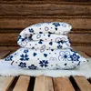 A stack of bedding with a floral pattern on a wooden background. Produktbild-Vorschau