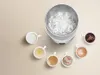 A white electric thermal vacuum hot water cup is surrounded by six small cups filled with different beverages, with steam rising from the cup. Náhled obrázku produktu