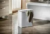 A white laundry basket with a towel draped over it sits on a tiled floor in a modern bathroom next to a bathtub. Podgląd zdjęcia produktu