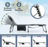 A gray foldable lounge chair is shown on a beach with palm trees in the background. The image highlights the chair's adjustable backrest and leg positions, as well as its storage pockets. Náhled obrázku produktu