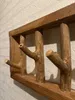 A close-up shot of a wooden coat rack with branch-like hooks, mounted on a textured white wall. Produktbild-Vorschau