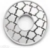 A close-up, top-down view of a silver-colored, circular object with a patterned design and a hole in the center, set against a white background. The pattern consists of repeating shapes resembling stylized clouds or leaves, outlined in dark gray. The Pokém Náhľad obrázku produktu