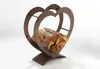 A heart-shaped metal log holder filled with firewood, set against a white background. Produktbild-Vorschau