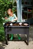 A young girl is planting seeds in a raised garden bed outdoors. Náhled obrázku produktu