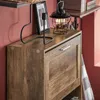 A close-up shot of a wooden shoe cabinet with a drawer and a flap door, decorated with a candle holder and a lantern. Produktbild-Vorschau