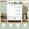 A white bathroom vanity with drawers and a door, set against a light green paneled wall. A basket of flowers is to the left, and a toilet and toilet brush holder are to the right. The bottom of the image features four icons with German text. Anteprima dell’immagine prodotto