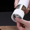 A person's hands are shown adjusting the grind setting on an electric pepper grinder. Podgląd zdjęcia produktu