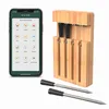 A smartphone displaying a cooking app next to a wooden knife block with knives and two meat thermometers. Podgląd zdjęcia produktu
