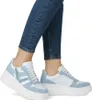 A close-up shot of a person's legs wearing blue jeans and light blue and white platform sneakers. Produktbild-Vorschau
