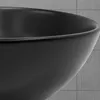 A close-up view of a black ceramic sink against a tiled background. Náhled obrázku produktu