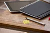 A desk with a tablet, notebook, pen, and a sticky note with tally marks. Produktbild-Vorschau