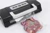 A vacuum sealer machine is shown sealing a piece of meat in a plastic bag. Podgląd zdjęcia produktu