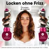 A woman is smiling at the camera, with two hair curling devices on either side of her, demonstrating how they curl hair. Produktbild-Vorschau