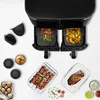 A top-down view of a dual-basket air fryer with food in both baskets, surrounded by various accessories and food items. Voir les images du produit