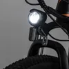 A close-up view of the front light and part of the tire of an electric bicycle. Produktbild-Vorschau