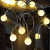 A string of warm white LED party lights with round bulbs is draped over a rustic wooden surface. Náhled obrázku produktu