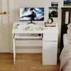 A white modern computer desk with a monitor, keyboard, mouse, headphones, books, and a mug on it. The desk is positioned in a room next to a bed. Podgląd zdjęcia produktu