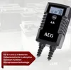 A black battery charger is shown in the foreground, with a background of car batteries. Produktbild-Vorschau