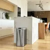 A modern kitchen with white cabinets, a marble island, and a stainless steel trash can. Produktbild-Vorschau
