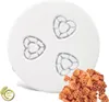A white pasta maker attachment with heart-shaped cutouts and a pile of heart-shaped pasta next to it. Produktbild-Vorschau