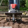 A person is using a tiller in a garden bed. Produktbild-Vorschau