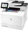 A white HP color laser printer is shown from a slightly elevated front-left angle, with a printed document partially ejected from the front. Podgląd zdjęcia produktu