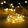 A close-up of a string of warm white LED lights coiled on a textured surface. Produktbild-Vorschau