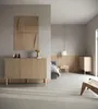A modern bedroom with a sideboard and a bed in the background. Produktbild-Vorschau