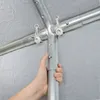 A hand is shown adjusting a metal pole connection on a tent frame. Voir les images du produit