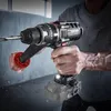 A person is holding a cordless drill, appearing to be in the process of drilling into a wall. Dust particles are visible in the air, suggesting active use. Produktbild-Vorschau