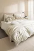 A neatly made bed with bedding and pillows in a bedroom setting. Anteprima dell’immagine prodotto