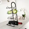 A black metal wine rack holding two bottles of wine on a light-colored countertop. Anteprima dell’immagine prodotto