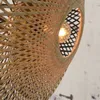 A close-up view of a woven bamboo lampshade with a light bulb visible inside. Anteprima dell’immagine prodotto