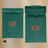 Two green mailboxes are shown side-by-side against a light brown background. The mailbox on the right is open, revealing a key in the lock. Anteprima dell’immagine prodotto