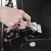 A hand is using a glass scraper to clean a stovetop. Produktbild-Vorschau