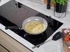 A frying pan with food being cooked on an induction stovetop. Produktbild-Vorschau