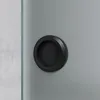 A close-up of a black circular sliding door handle on a gray sliding door. Produktbild-Vorschau