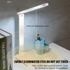 A white LED desk lamp is shown on a desk next to some books and a pen holder. Produktbild-Vorschau