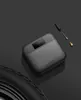 A portable electric air compressor is shown on a dark surface next to a tire. Produktbild-Vorschau