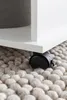 A close-up view of a white rolling table leg on a textured rug. Voir les images du produit