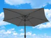 A grey rectangular patio umbrella is shown against a blue sky with white clouds. Produktbild-Vorschau