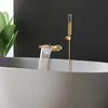 A modern bathroom with a bathtub and a gold waterfall faucet with a handheld showerhead. Podgląd zdjęcia produktu