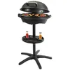A black electric grill with its lid open, showing food cooking on the grill surface. It is mounted on a stand with a tray holding two bottles of sauce. Produktbild-Vorschau