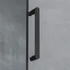 A close-up of a black shower door handle against a gray concrete-like background. Produktbild-Vorschau