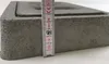 A close-up side view of a gray concrete chimney flap with a ruler measuring its height. Náhľad obrázku produktu