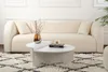 A white couch and a white coffee table are in a living room setting, with a rug on the floor. Produktbild-Vorschau