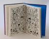 An open book displaying a detailed black and white illustration on its pages, with a blue endpaper visible on the right. Podgląd zdjęcia produktu