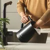 A person is cleaning a black electric kettle in a kitchen sink. Podgląd zdjęcia produktu